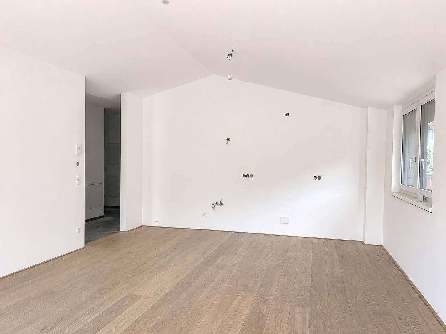 Unmöblierter Wohnbereich mit Holzboden und schrägen Decken, bereit zur individuellen Gestaltung.