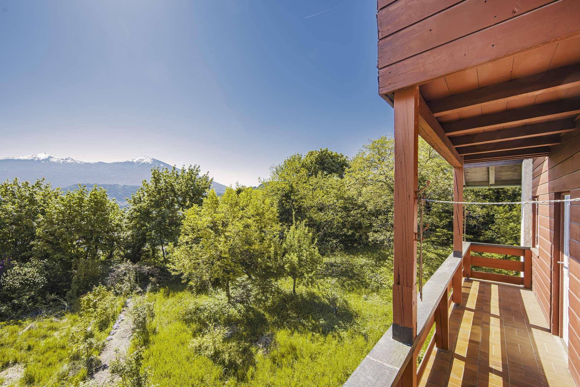 Geräumiger Holzbalkon mit malerischem Blick auf die grüne Landschaft und die majestätischen Berge.