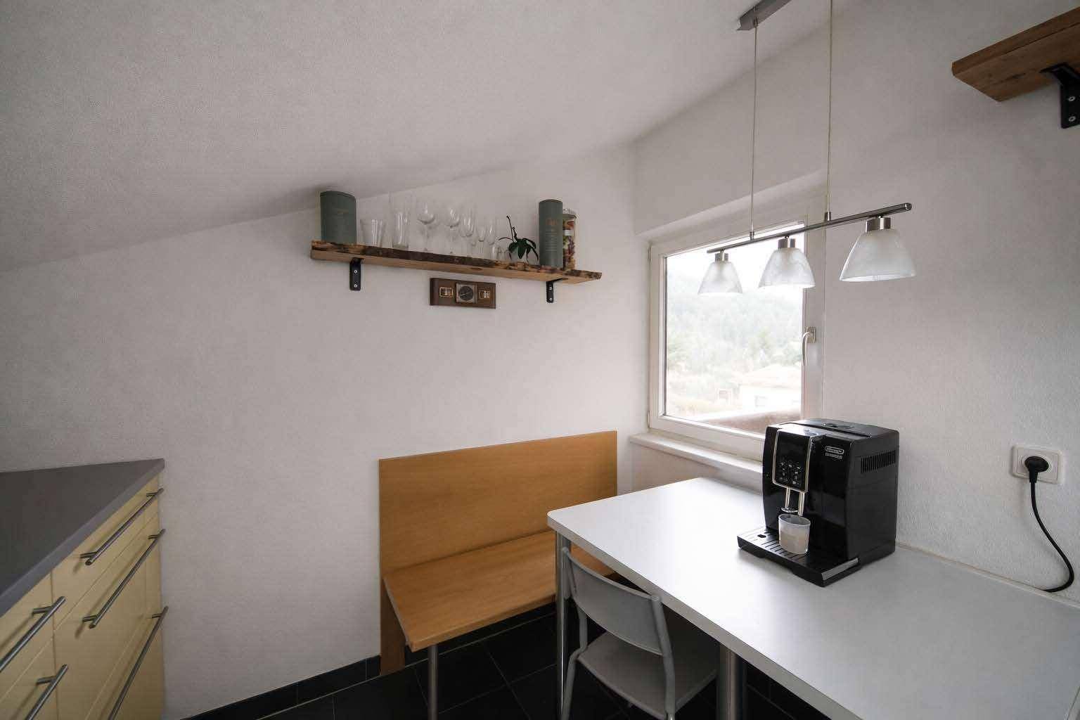 Heller Essbereich in der Küche mit Fenster, Bank und Kaffeemaschine für gemütliche Mahlzeiten.