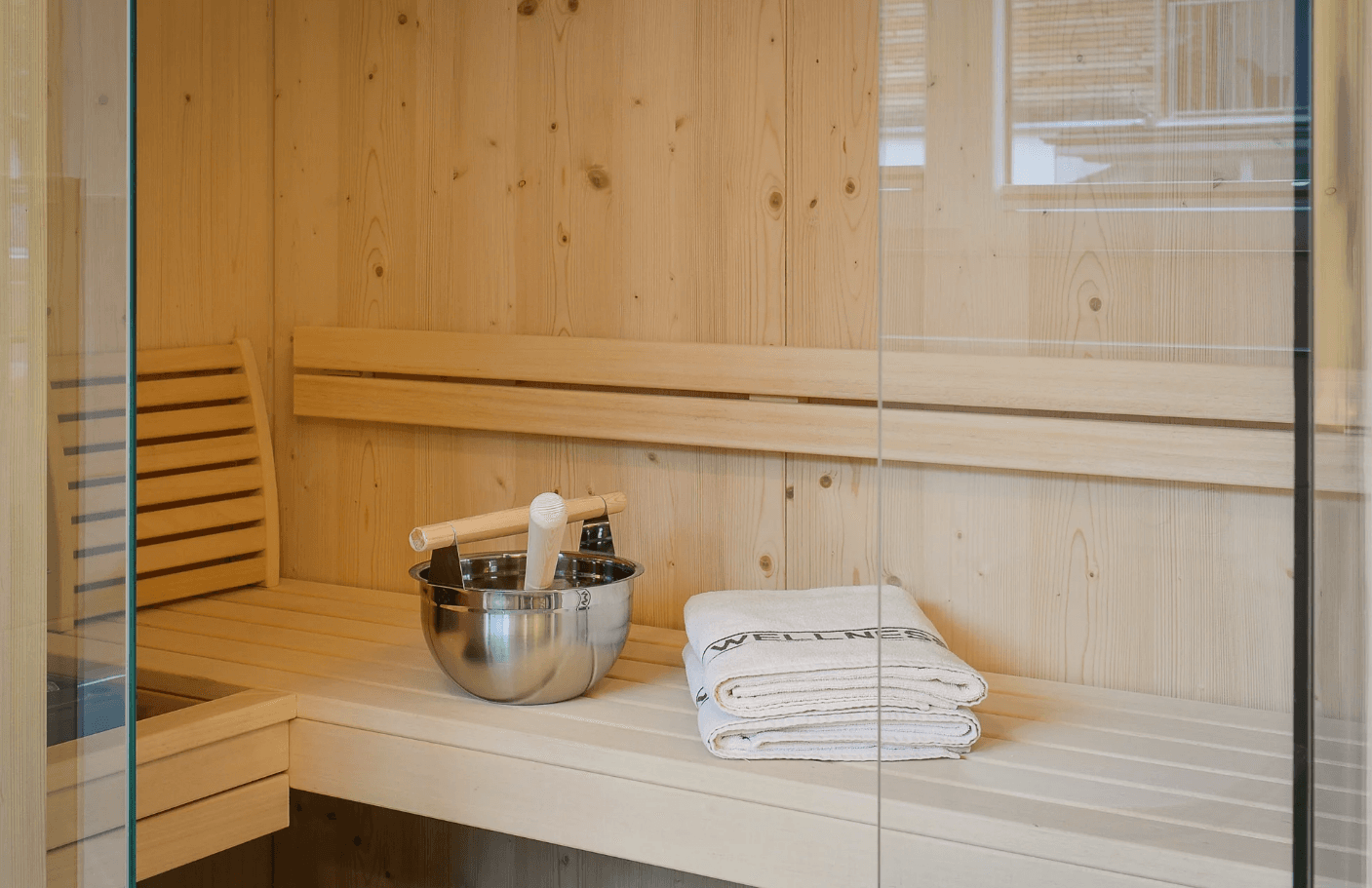 Moderne Holzsauna mit Bänken, Eimer und Handtüchern für entspannende Momente.