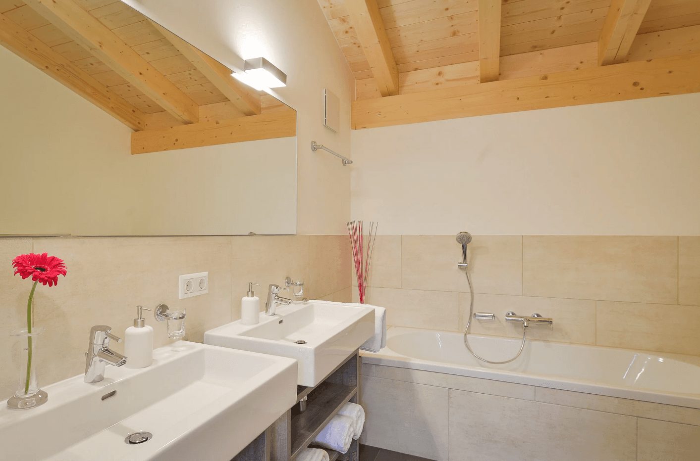 Modernes Badezimmer mit Doppelwaschbecken, Badewanne und Holzbalkendecke.