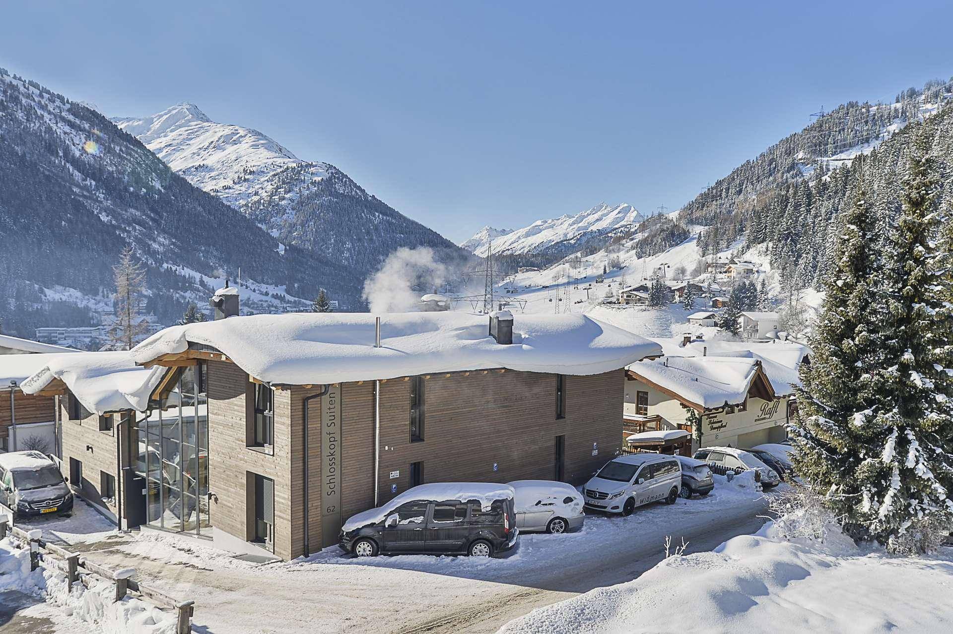 Gebäudeansicht im Winter mit verschneiter Landschaft und umliegenden Bergen.