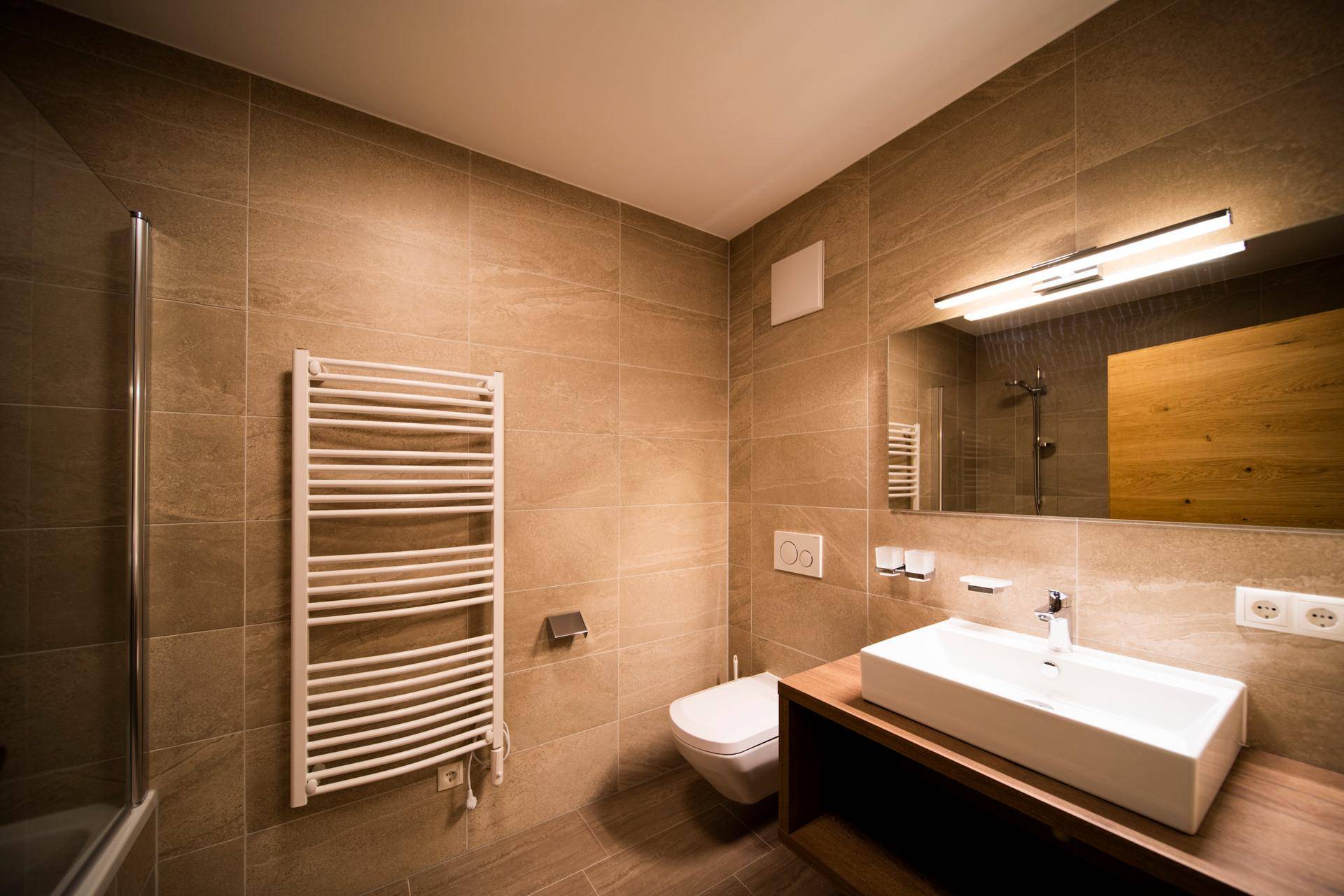 Modernes Badezimmer mit Waschtisch, Wand-WC und beheiztem Handtuchtrockner.