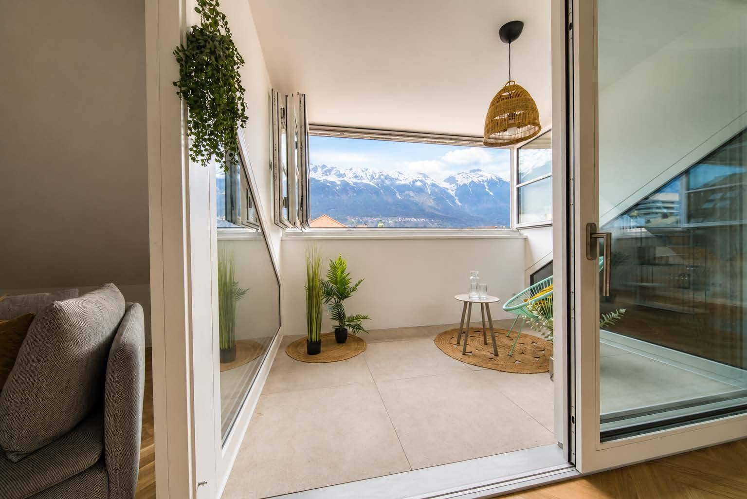 Verglaster Balkon mit atemberaubendem Bergblick, eingerichtet als gemütlicher Sitzbereich.