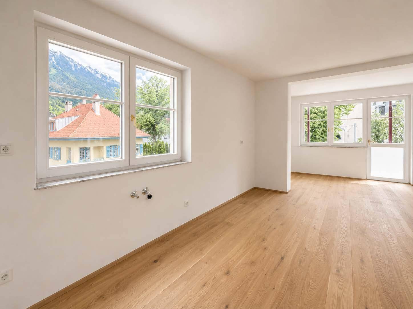 Heller Wohnbereich mit Parkettboden, Bergblick und Vorbereitung für eine Küchenzeile.