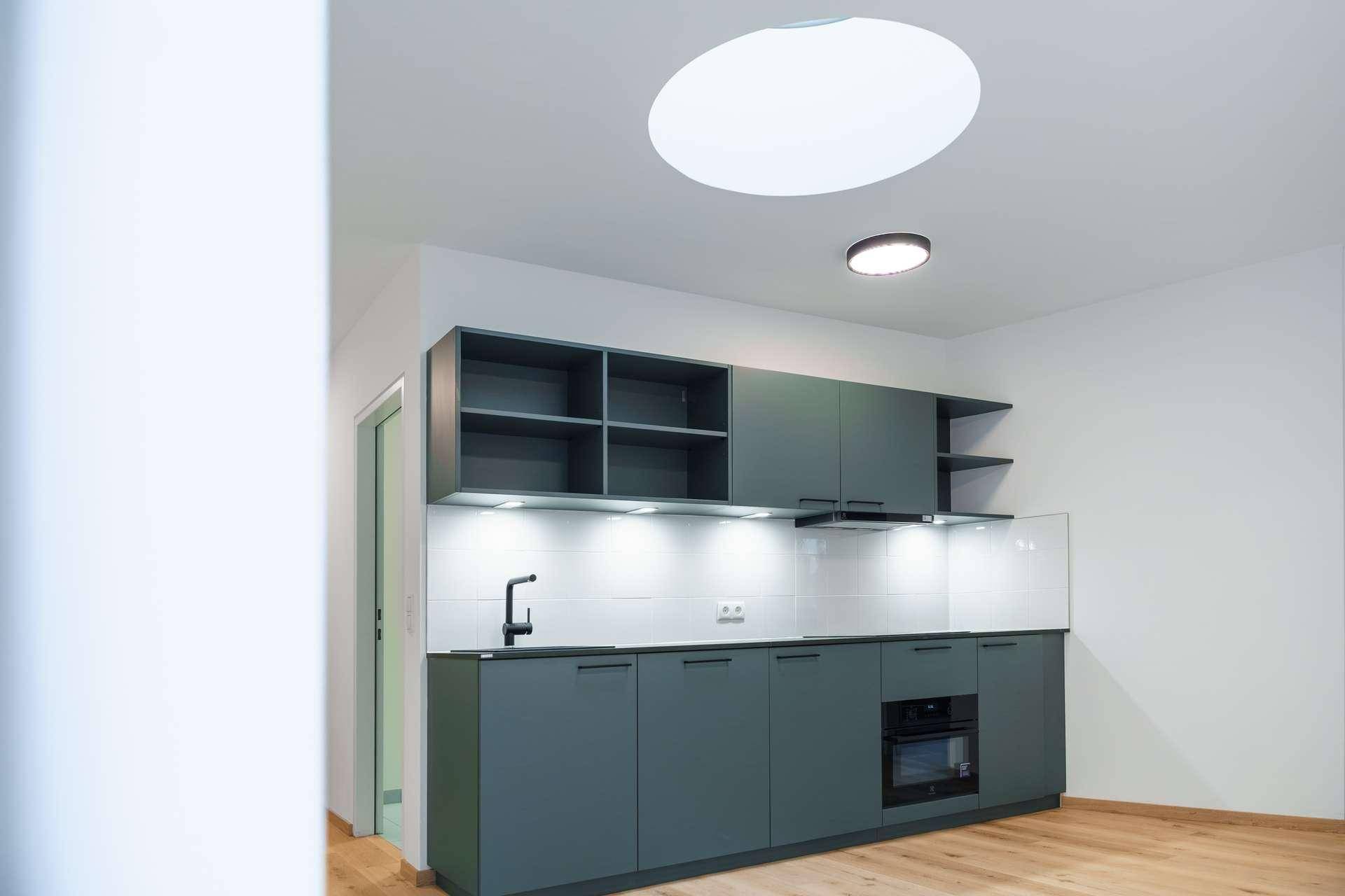 Moderne Küchenzeile mit grauen Schränken, integrierten Geräten und Holzfußboden.