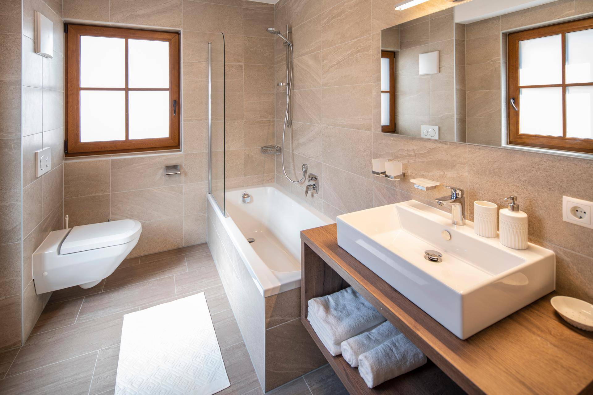 Funktionales Badezimmer mit Badewanne, Dusche, WC und Fenster für Tageslicht.