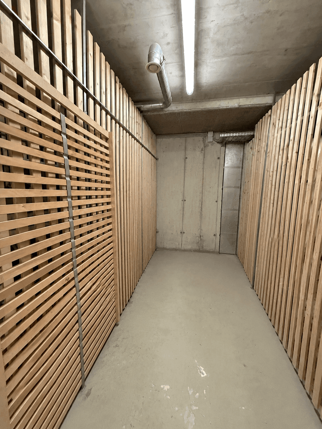 Geräumiger Abstellraum im Keller mit Holzabtrennungen und Betonboden.