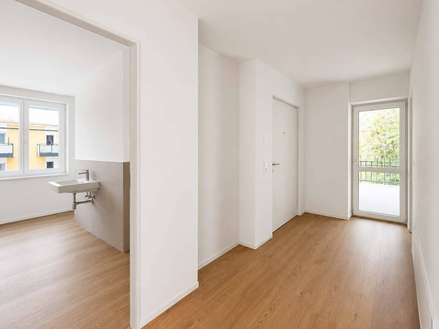 Heller Flur mit Laminatboden und Zugang zu einem Badezimmer oder Gäste-WC sowie Balkon.