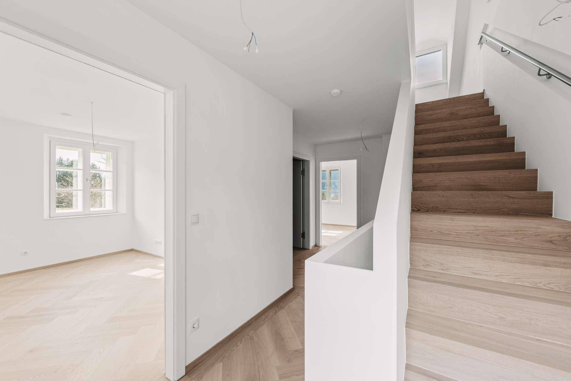 Heller Flur mit Holztreppe und Zugang zu weiteren Räumen.