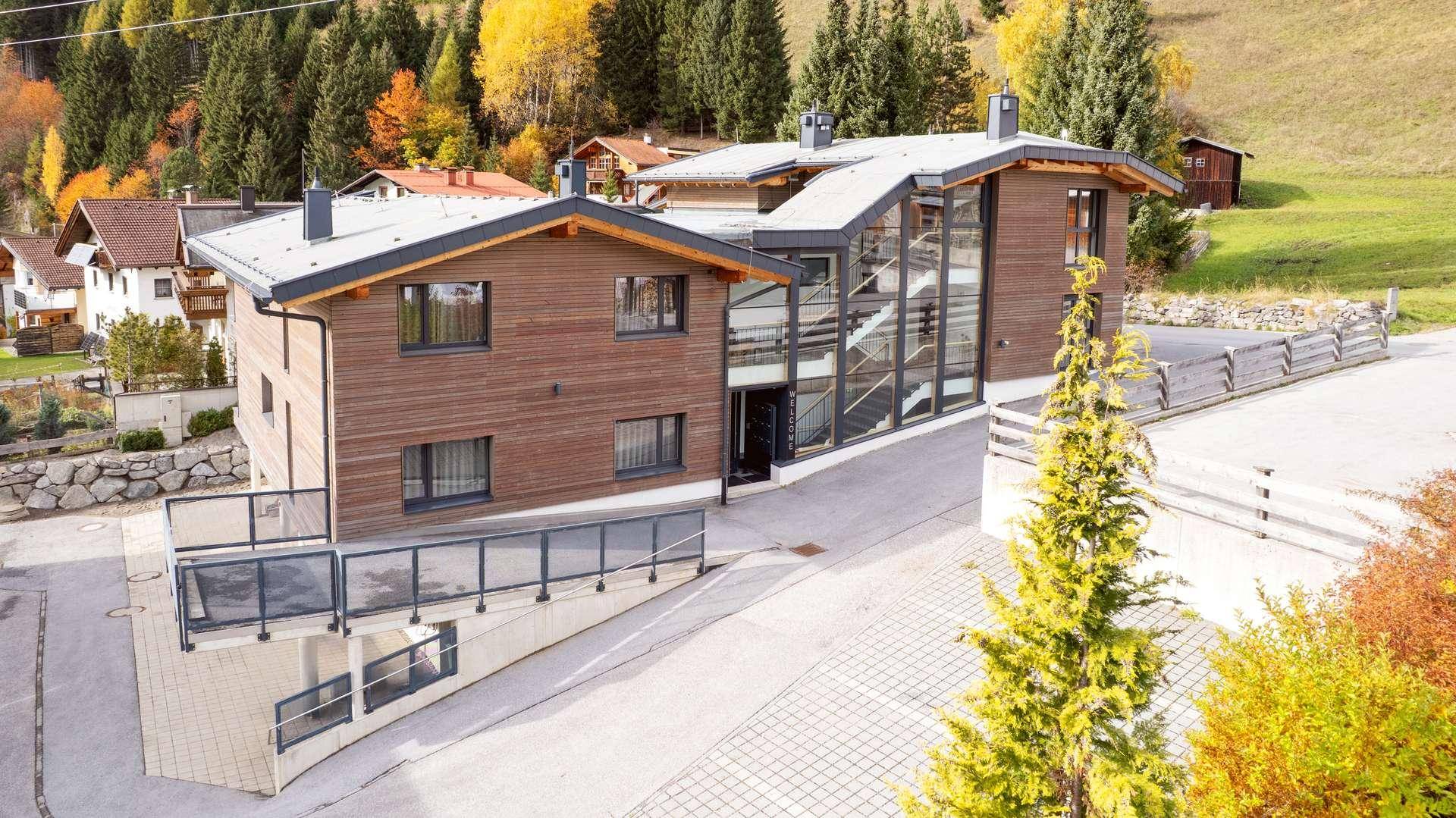 Moderne Architektur des Gebäudes mit Holzfassade und großen Glasflächen in alpiner Umgebung.