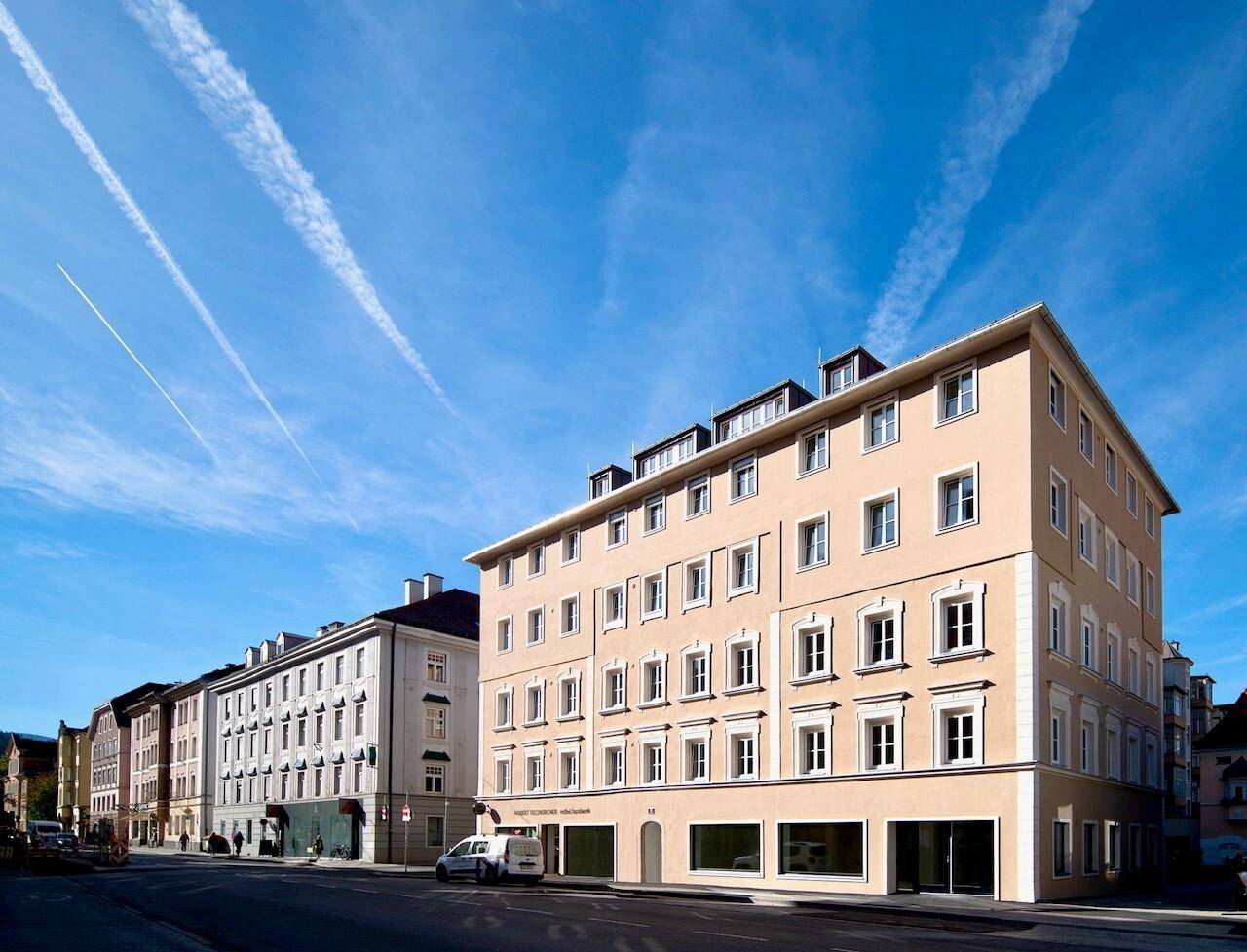 Attraktives Mehrfamilienhaus mit klassischer Fassade und vielen Fenstern unter blauem Himmel.
