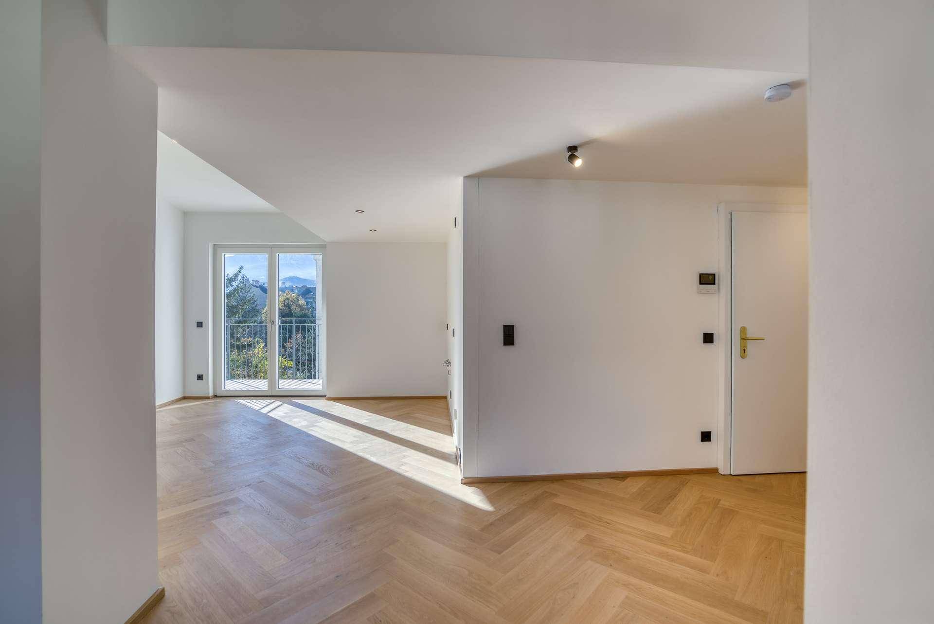 Unmöblierter Eingangsbereich mit Fischgrätparkett und Zugang zu einem französischen Balkon.