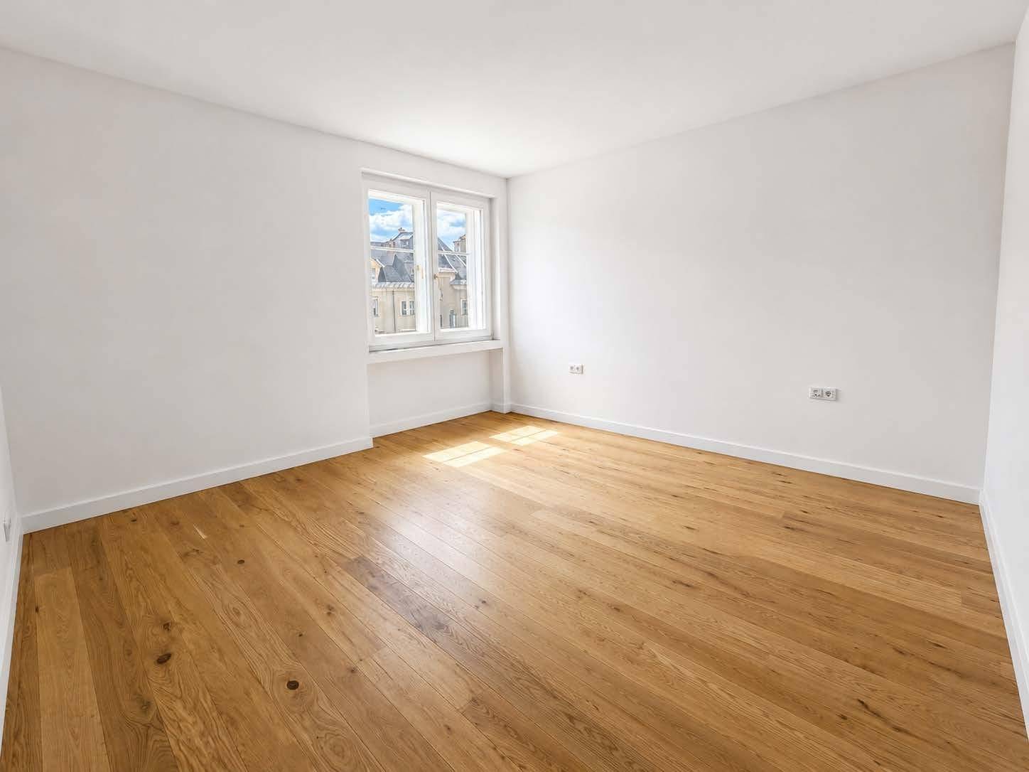 Helles Schlafzimmer mit Parkettboden und Blick auf die umliegende Stadtarchitektur.