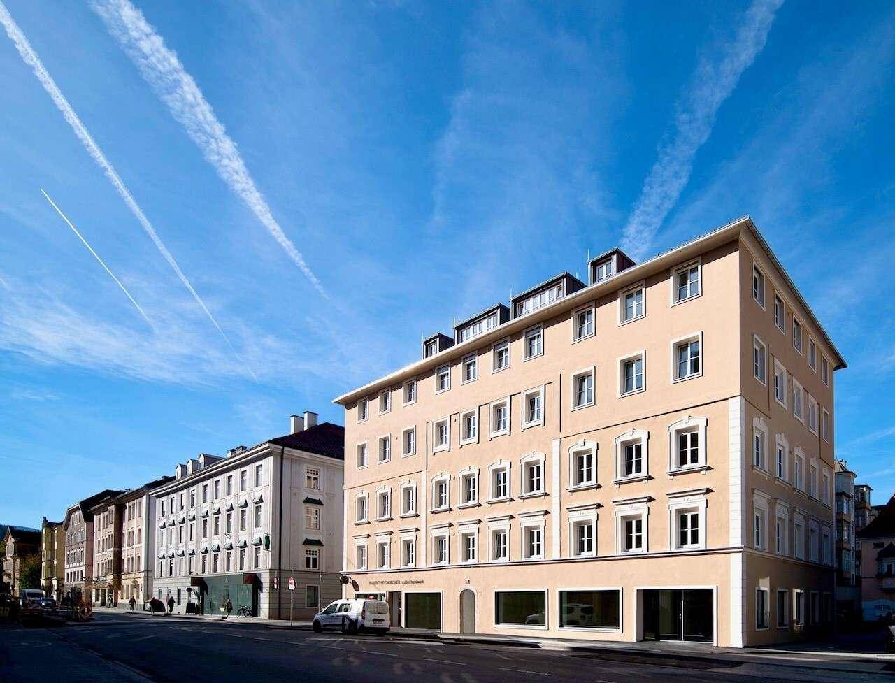 Attraktives Mehrfamilienhaus mit heller Fassade und vielen Fenstern unter blauem Himmel.