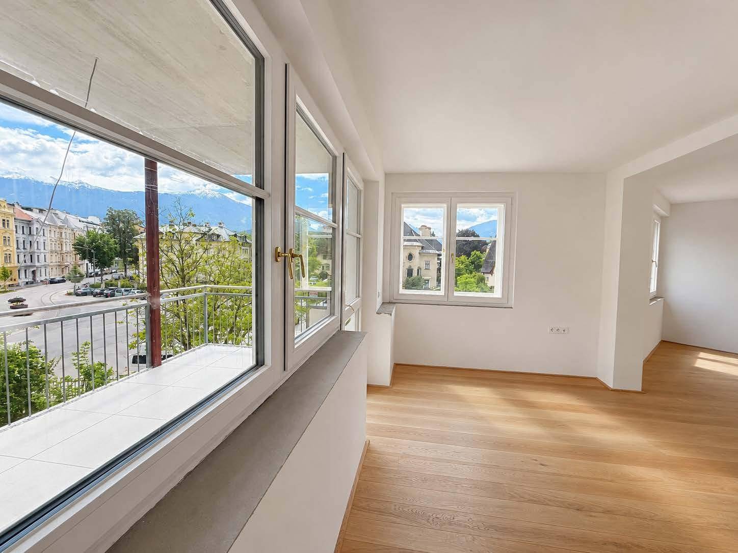 Lichtdurchflutetes Wohnzimmer mit Bergblick und Zugang zu einem französischen Balkon.