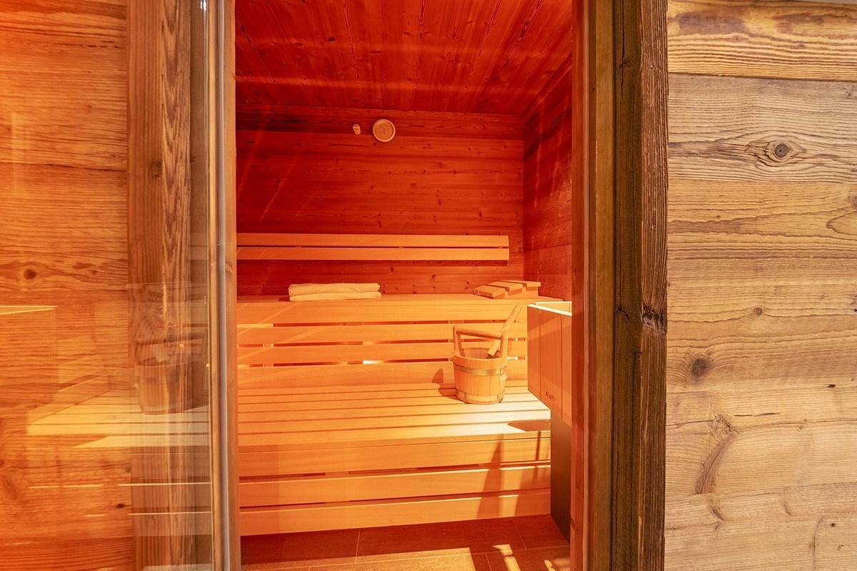 Traditionelle Holzsauna mit Bänken und Saunaofen für entspannende Momente.