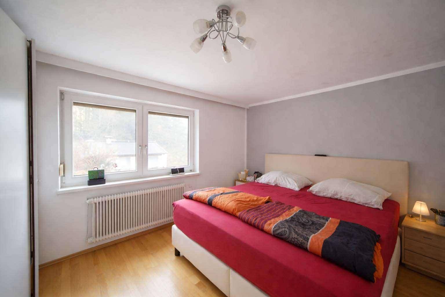 Gemütliches Schlafzimmer mit Doppelbett, Holzboden und Fenster mit Ausblick.