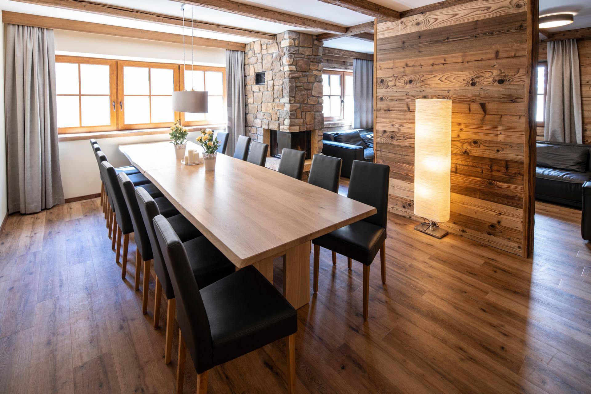 Geräumiger Essbereich mit langem Holztisch, Steinwandkamin und Holzbalkendecke.