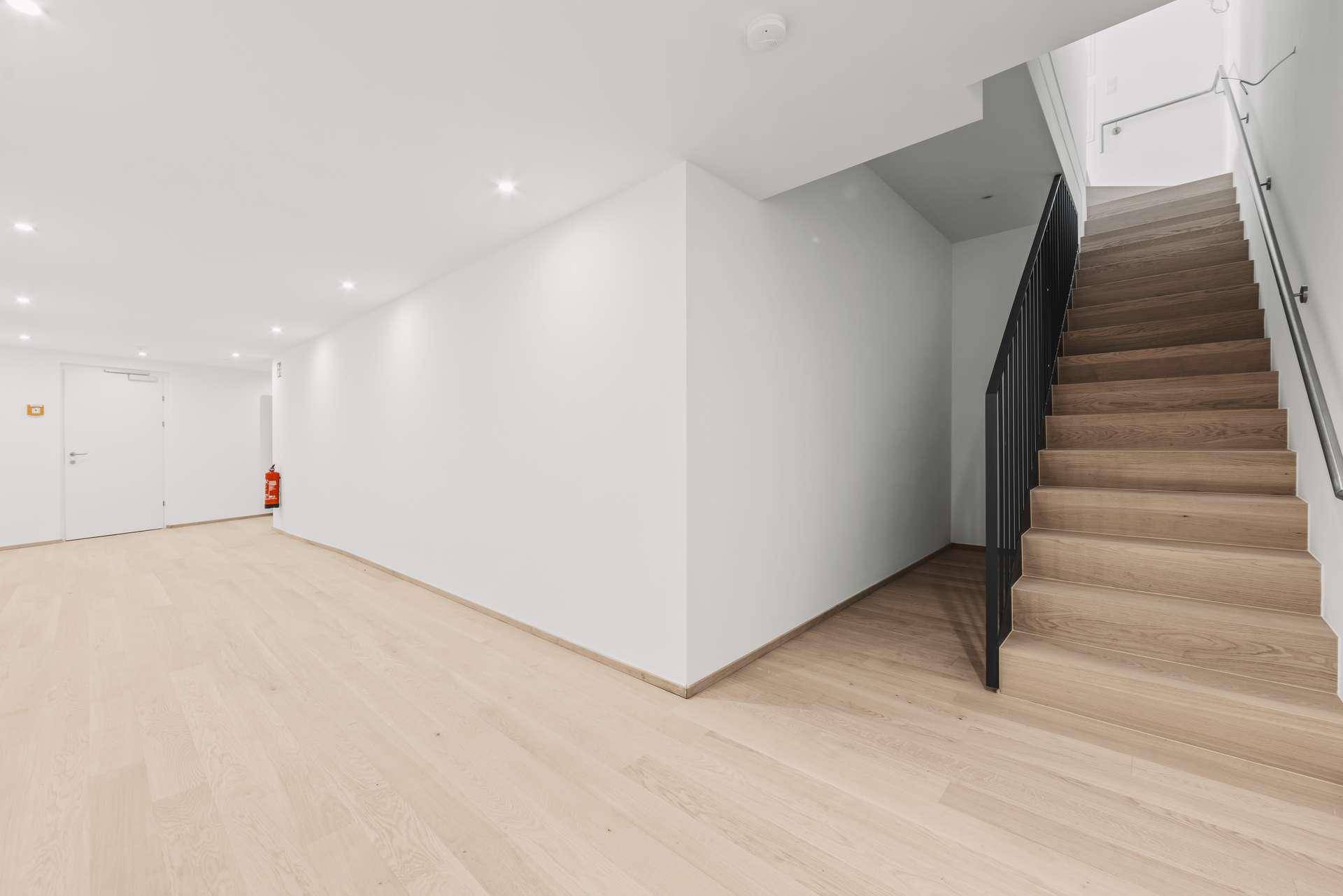 Geräumiger Kellerbereich mit Holztreppe und moderner Beleuchtung.