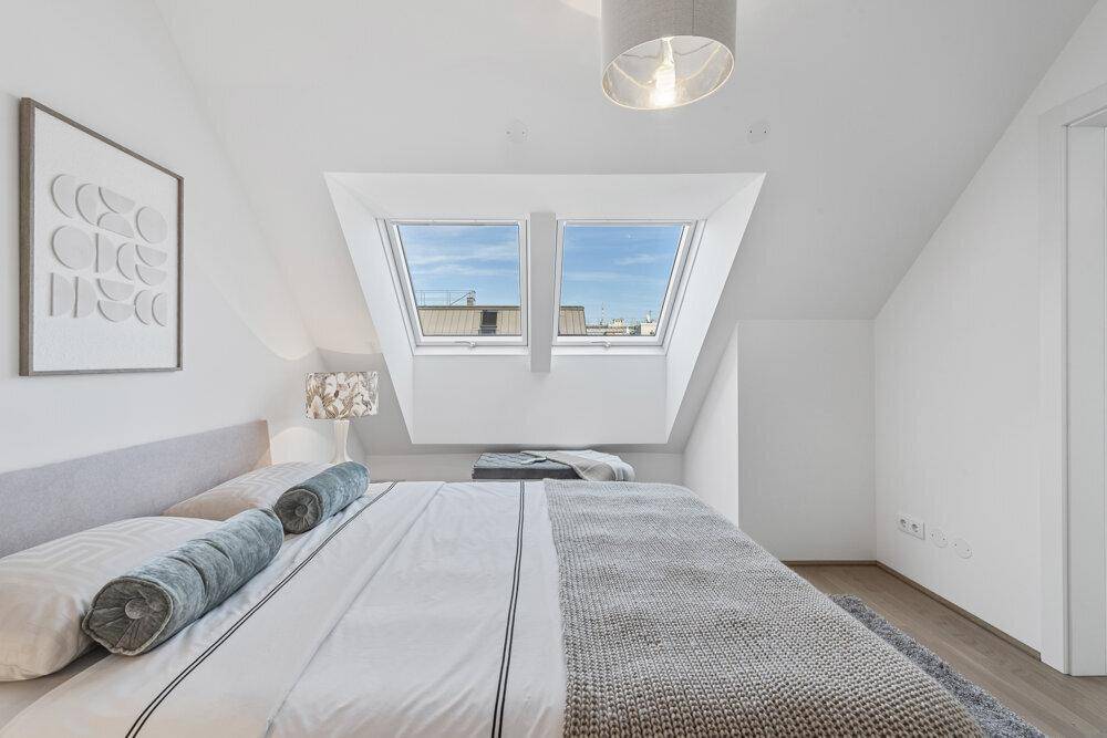 Schlafzimmer mit zwei Dachfenstern, hellem Interieur und gemütlichem Doppelbett.