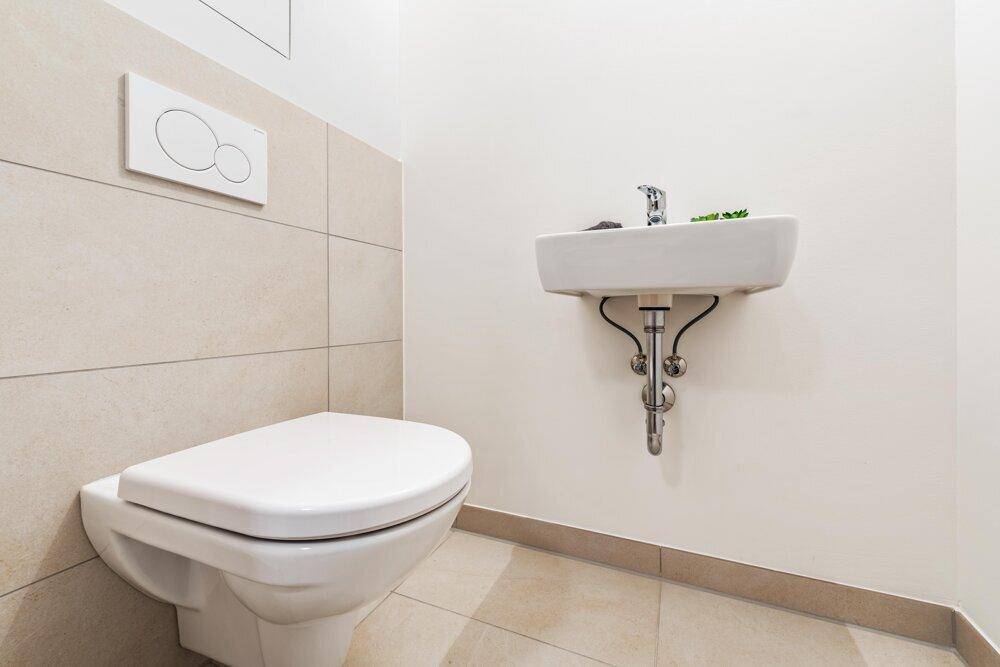 Modernes Gäste-WC mit wandhängender Toilette und kleinem Waschbecken.