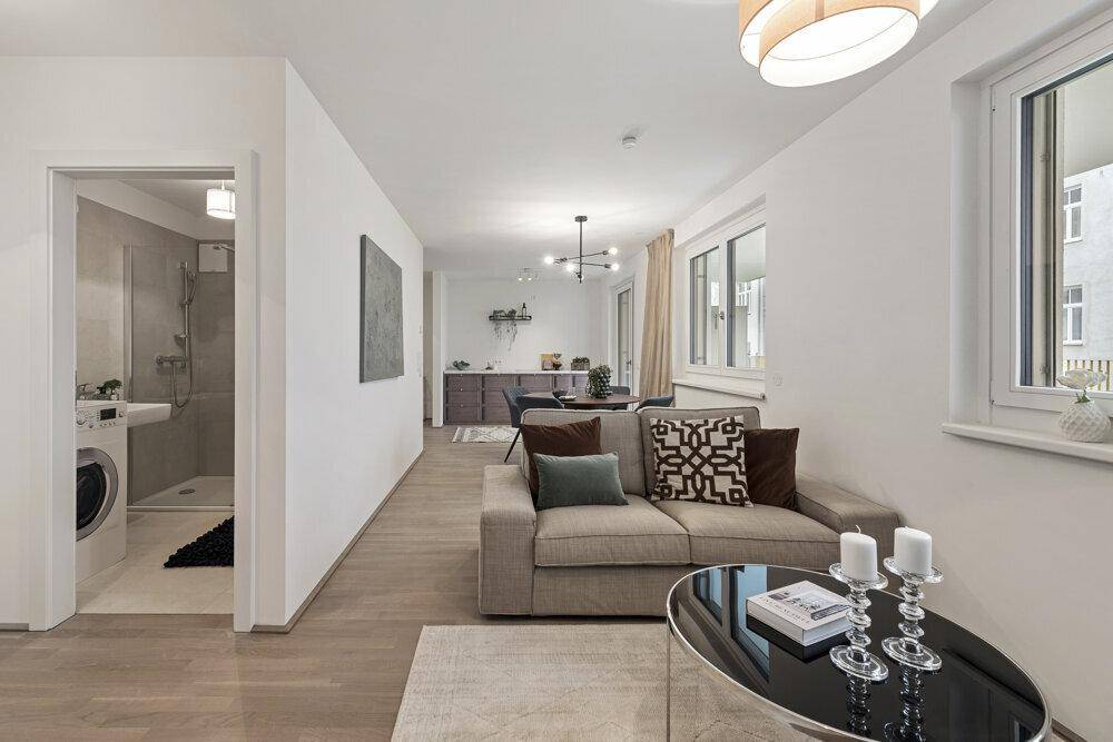 Heller offener Wohn- und Essbereich mit Holzboden und Blick ins Badezimmer.