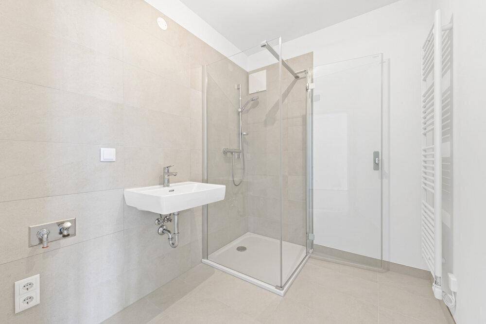 Modernes Badezimmer mit Duschkabine, Waschbecken und praktischem Handtuchheizkörper.