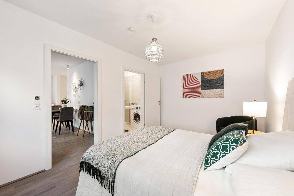 Modernes Schlafzimmer mit Holzboden und Zugang zu Essbereich und Bad.