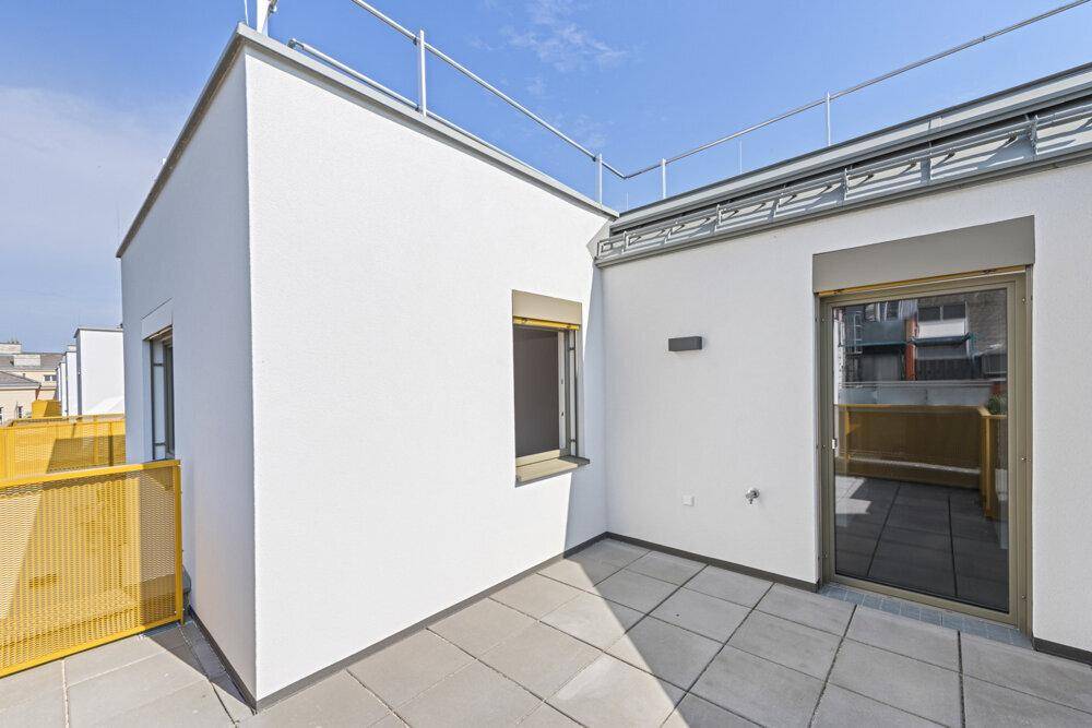 Dachterrasse mit grauen Fliesen und gelbem Geländer, bietet einen weiten Blick über die Stadt.