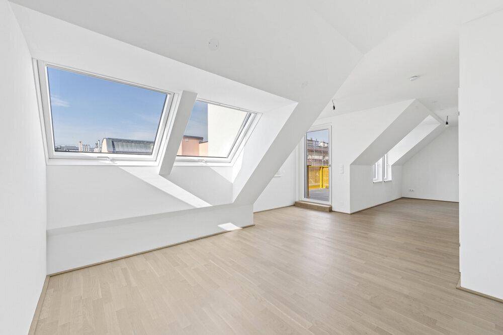 Leerer Raum mit hellen Holzböden, Dachfenstern und Zugang zur Terrasse im Dachgeschoss.