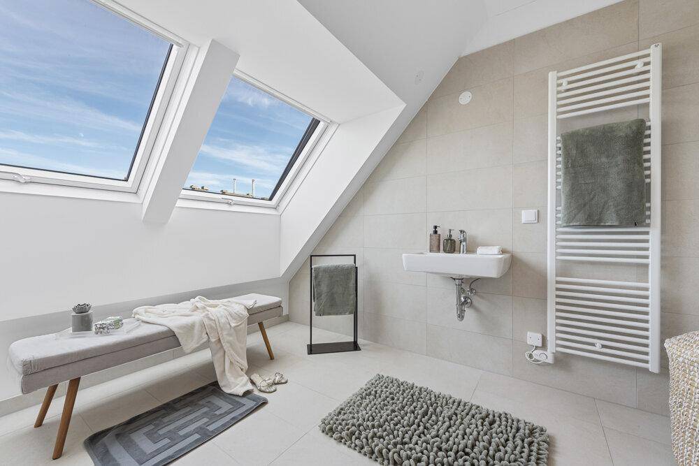 Modernes Badezimmer mit Dachfenstern, hellem Fliesenboden und Handtuchheizkörper.