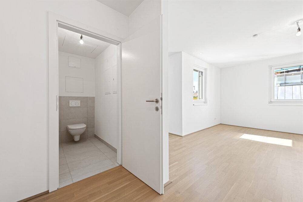Heller Flur mit Zugang zu einem Gäste-WC und Blick in den offenen Wohnbereich.