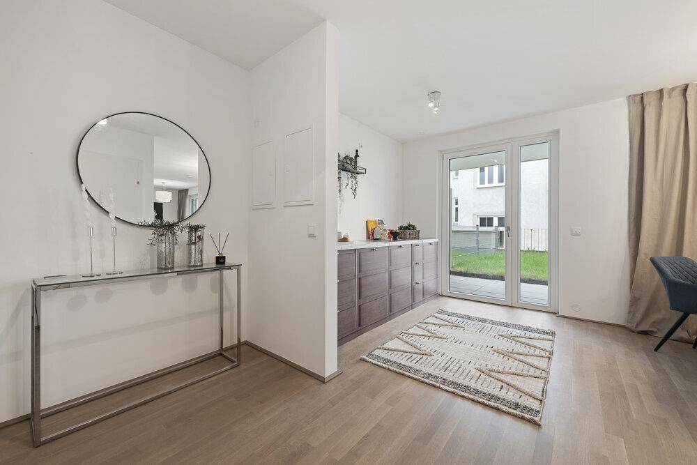 Moderner Eingangsbereich mit Spiegel, Konsole und Zugang zu einer Terrasse oder Gartenfläche.