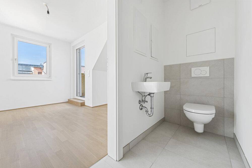 Modernes Gäste-WC mit Wand-WC, kleinem Waschbecken und Fliesenboden.
