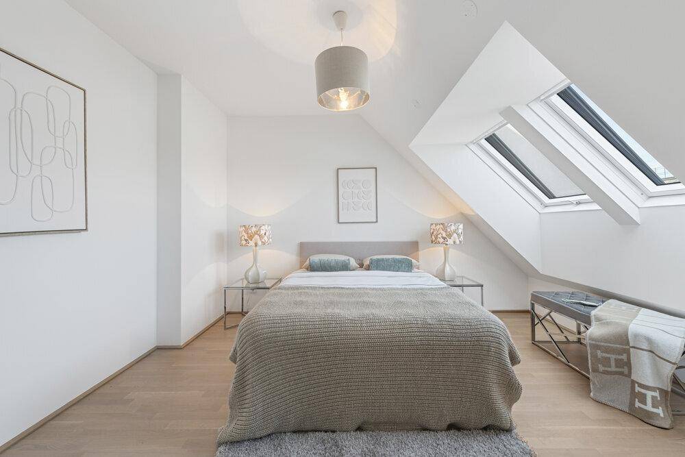 Geräumiges Schlafzimmer mit Dachschrägen, Parkettboden und modernem Bett.