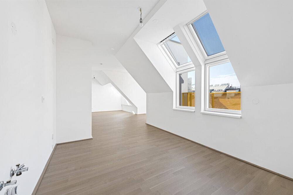 Geräumiger, heller Raum mit Holzboden und großen Fenstern im Dachgeschoss.