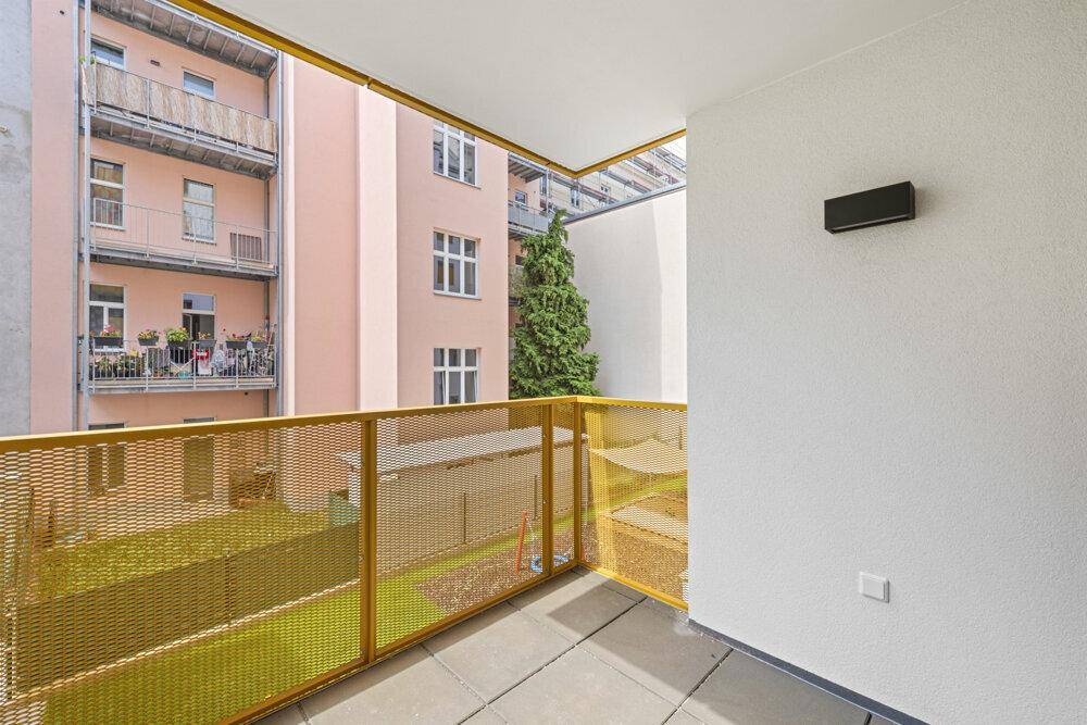 Balkon mit gelbem Geländer und Blick auf den Innenhof.
