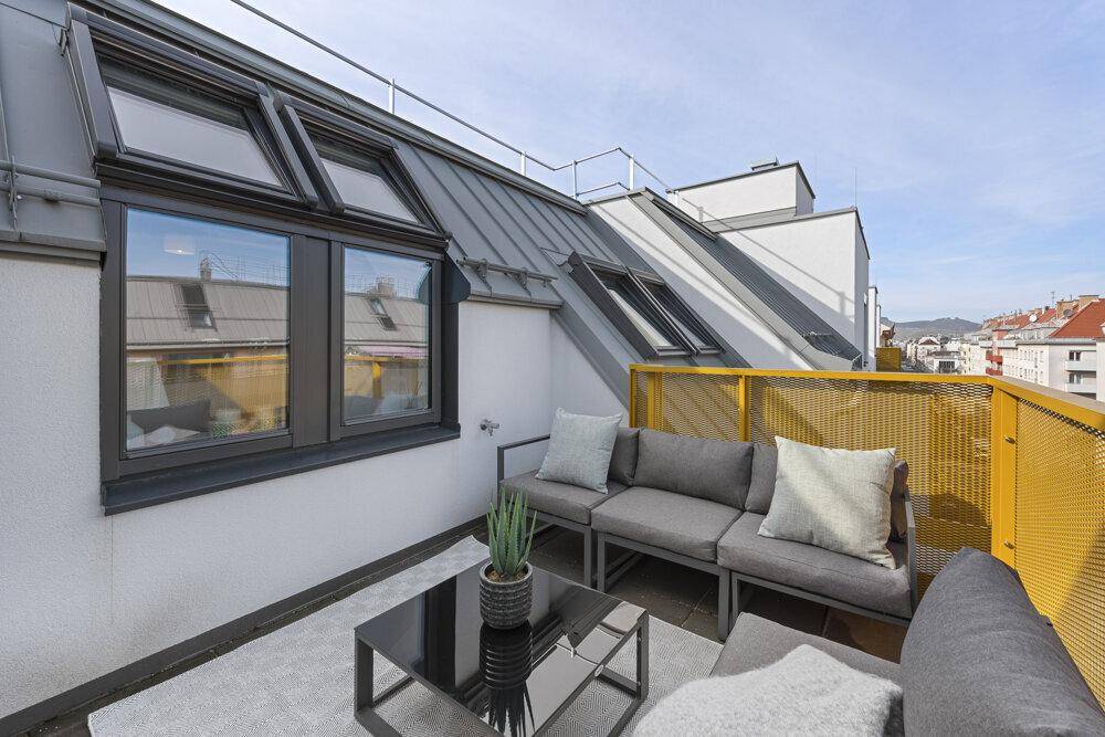 Möblierte Dachterrasse mit gemütlicher Sitzecke und Blick über die Stadt.