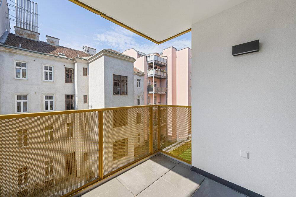 Balkon mit gelbem Gitter und Blick auf den ruhigen Innenhof der Wohnanlage.