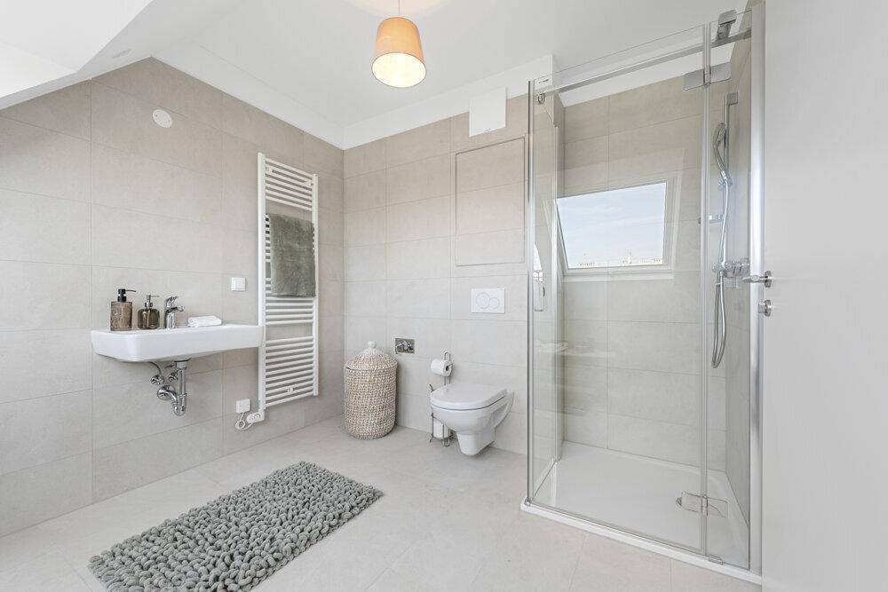 Modernes Badezimmer mit Duschkabine, WC, Waschtisch und Handtuchheizkörper.