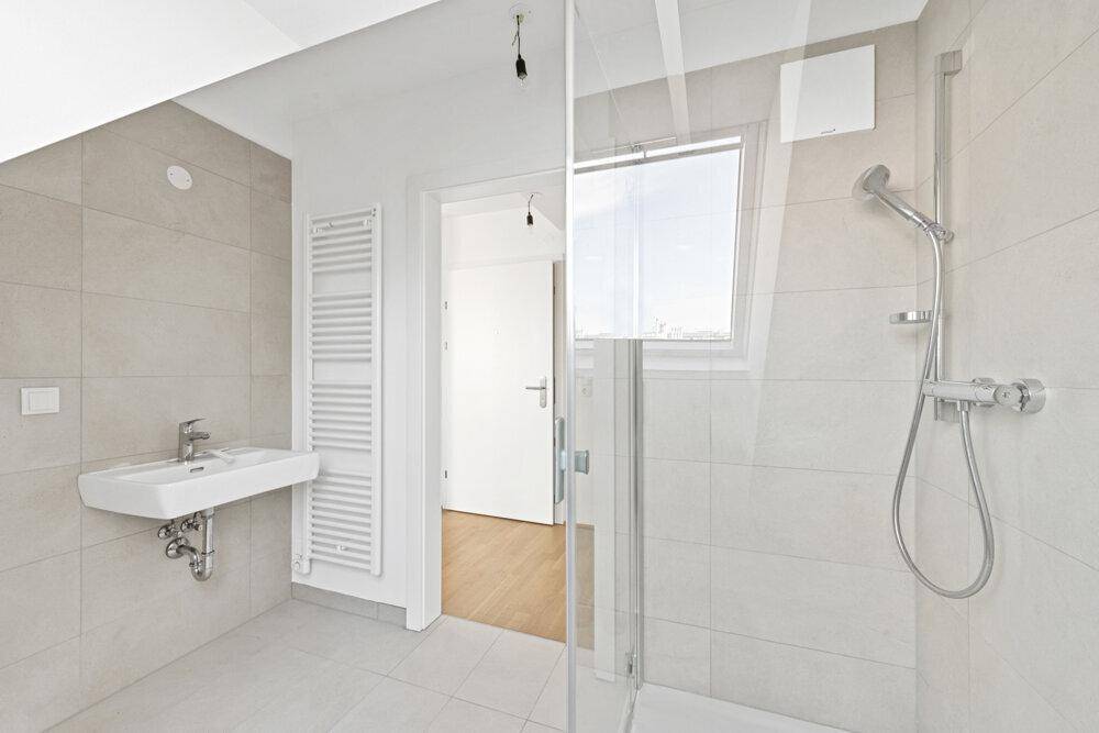 Modernes Badezimmer mit Dusche, Waschbecken, Handtuchheizkörper und Fliesen.