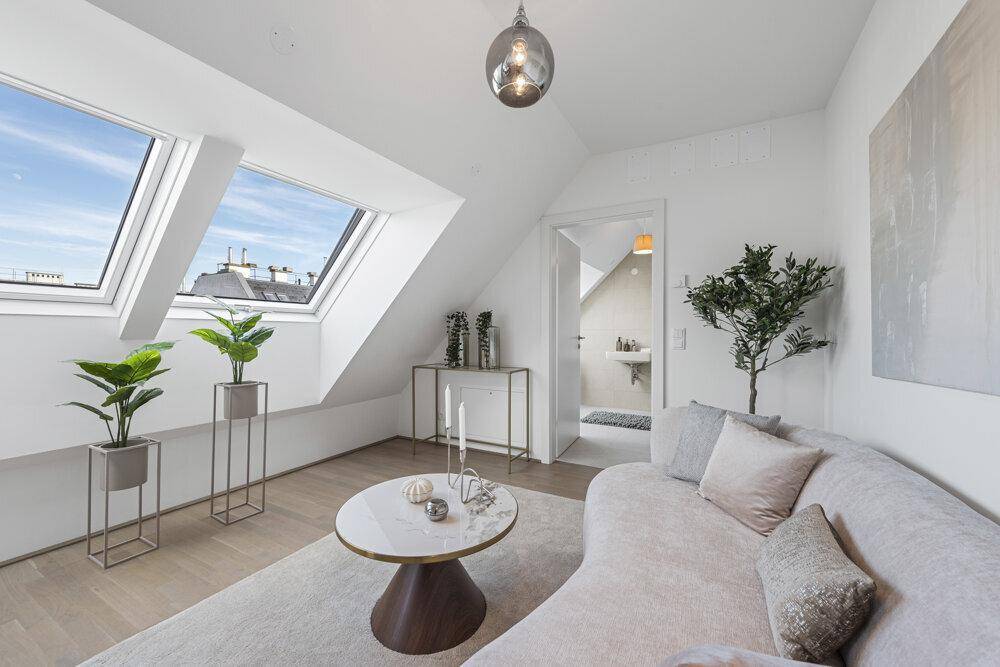 Helles Wohnzimmer mit Dachschrägen, Dachfenstern und Blick ins angrenzende Badezimmer.