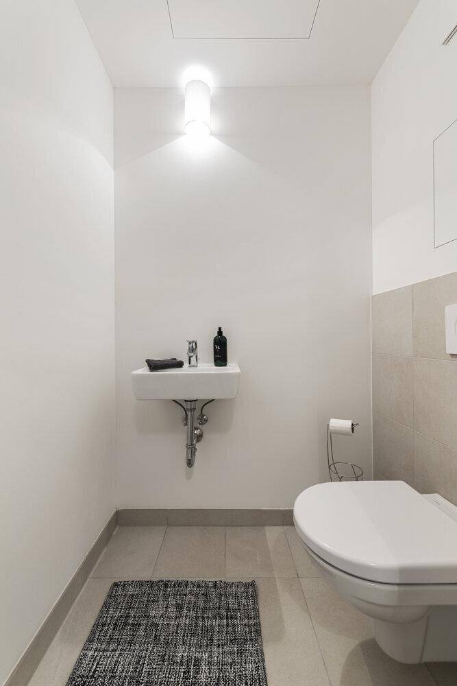 Kleines, helles Gäste-WC mit wandhängendem WC und modernem Waschbecken.