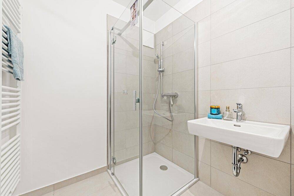 Helle Duschkabine mit Glaswänden und modernem Waschbecken im Badezimmer.