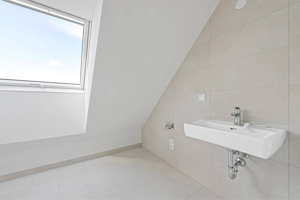 Modernes Badezimmer mit Waschbecken, Fliesen und Dachfenster für Tageslicht.