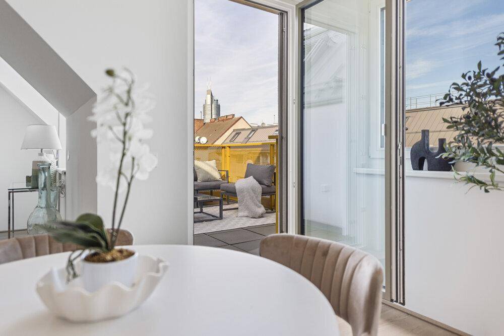 Blick vom Essbereich auf die möblierte Terrasse und die Stadtkulisse.