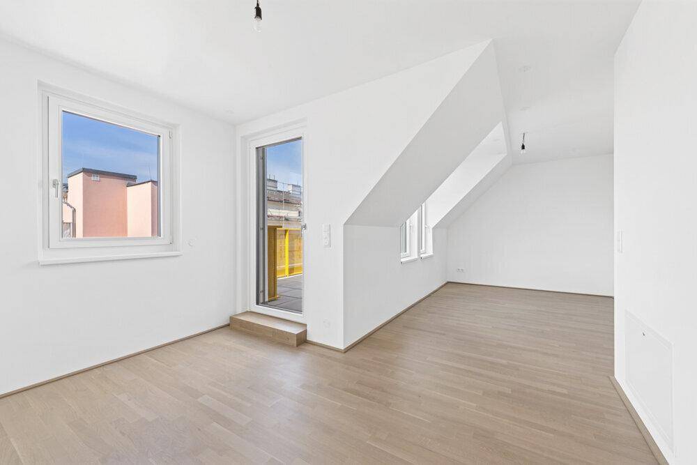 Heller Raum mit Holzboden, Fenster und Terrassenzugang im Dachgeschoss.