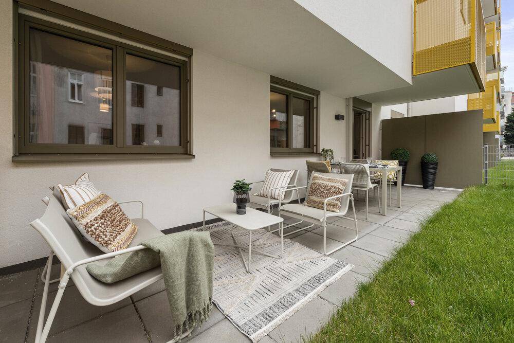 Gemütliche Terrasse mit Lounge-Möbeln und Blick auf den angrenzenden Rasenbereich.