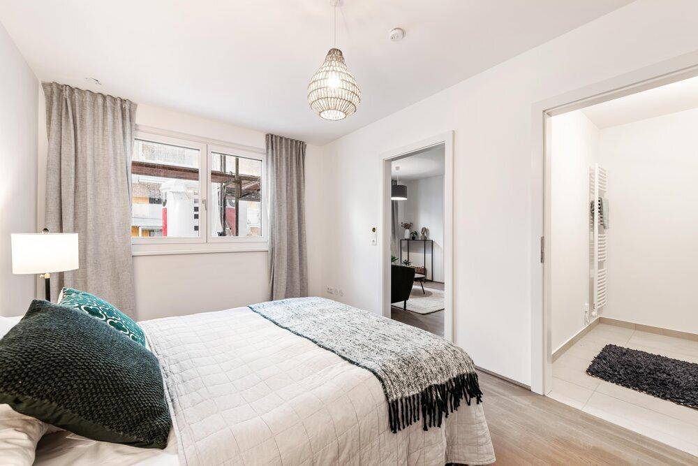 Schlafzimmer mit großem Fenster, Doppelbett und direktem Zugang zum Badezimmer.